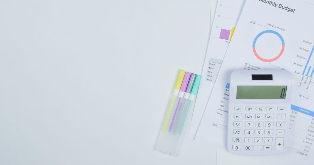 50/30/20 Budget Planning with Calculator and Notebook Monthly budget planning with a calculator, budget notebook, and colorful pens arranged on a clean office desk — representing the 50/30/20 budgeting method