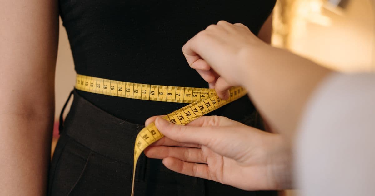 Body Measurement with Measuring Tape — New BMI Calculator Guide Person measuring waist circumference with yellow measuring tape — a body measurement technique used alongside the new Trefethen BMI formula to assess body composition